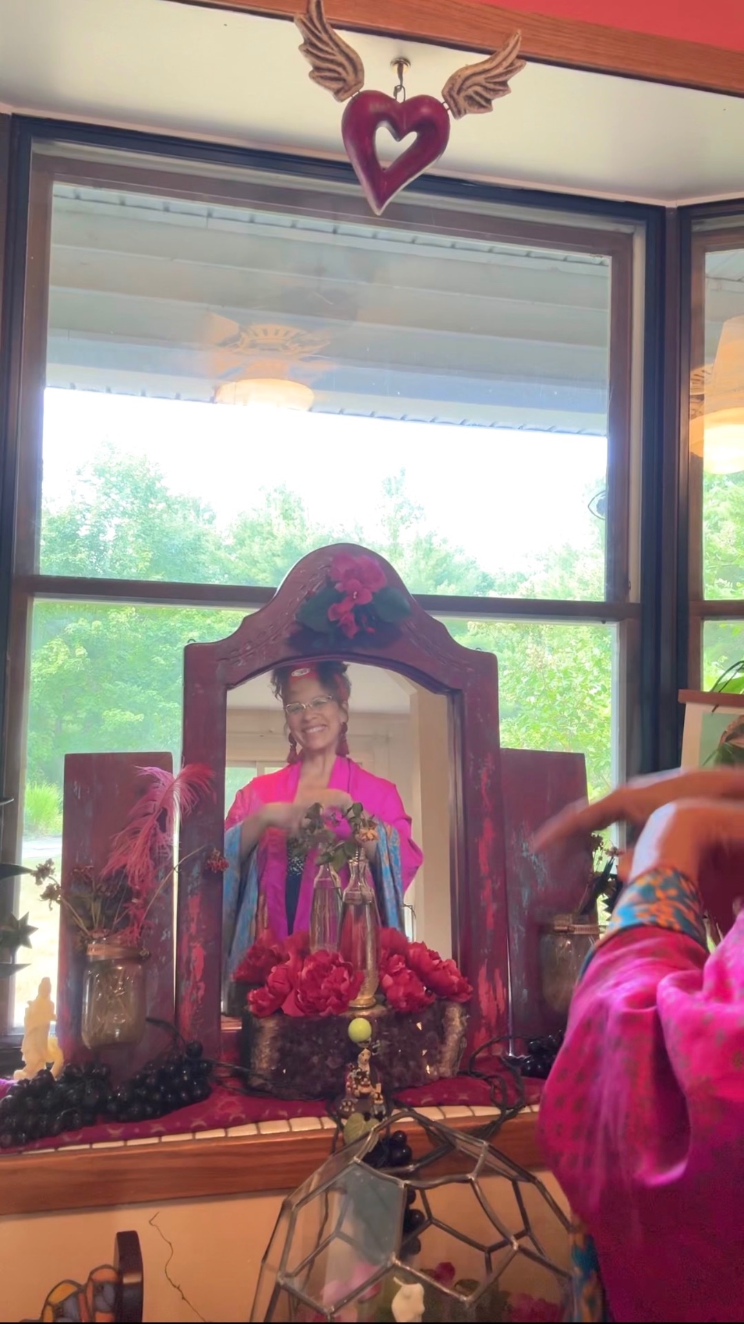 Reverent Mariela reflected in a rose-painted mirror shrine, dressed in pink silk